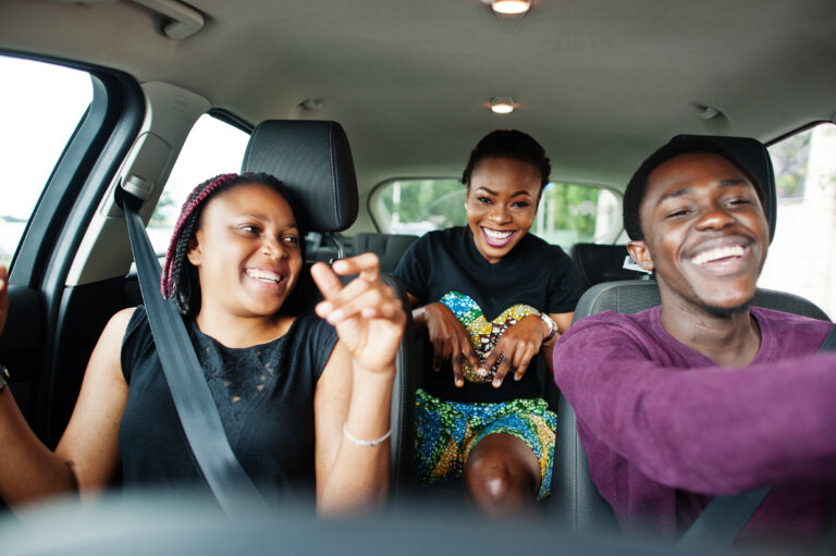 young african american friends sitting inside a car.
